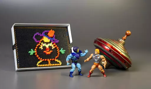 This undated photo provided by The Strong Museum shows the three toys inducted into the National Toy Hall of Fame on Nov. 10, 2022, in Rochester, N.Y. Masters of the Universe, Lite-Brite and the top were chosen from among 12 finalists for the annual honor, which recognizes toys that have inspired creative play and lasting popularity. (Courtesy of The Strong Museum via AP)