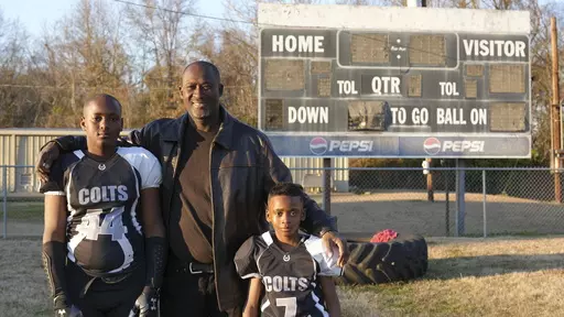 This photo provided by the University of Maryland shows Ronald Redmond standing with sons, 11-year-old R.J., left, and 7-year-old Mason on a football field in Lexington, Mississippi, Jan. 4, 2024. Lexington, Miss. is located in the second-poorest county in the nation’s poorest state. Yet a new analysis shows the town sends more players per capita to elite college football programs than any other town in Mississippi – at a rate that’s among the top in the nation. For many families, the game