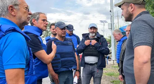 In this photo released by the International Atomic Energy Agency, the Director General of nuclear watchdog, Rafael Mariano Grossi, second from left, speaks to unidentified authorities as the UN agency mission heads to the Zaporizhzhia nuclear power plant, Zaporizhzhia, Ukraine, Thursday, Sept. 1, 2022. The IAEA mission has been delayed on the Ukrainian-controlled side of the frontline for some three hours. Director General Grossi has personally negotiated with Ukrainian military authorities to b
