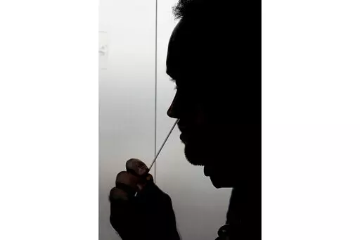 A rapid COVID-19 test is taken, Wednesday, Nov. 18, 2020, in Salt Lake City. President Joe Biden says the federal government will buy half a billion COVID-19 rapid test kits and distribute them free of charge to people to use at home. Delivery of the first batch of the 500 million tests isn't expected until early January 2022. (AP Photo/Rick Bowmer, File)