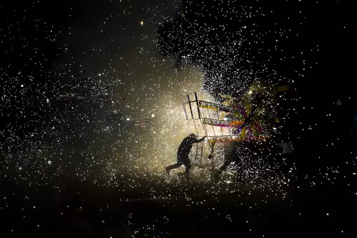 Residents push a giant paper-mache "torito" or bull stuffed with fireworks during a nighttime lighting of bull-shaped figures as part of the annual festival honoring Saint John of God, in Tultepec, Mexico, Friday, March 8, 2024. The celebration, now its 35th year, pays homage to the patron saint of the poor and sick, St. John of God, who the fireworks' producers view as a protective figure. (AP Photo/Marco Ugarte)