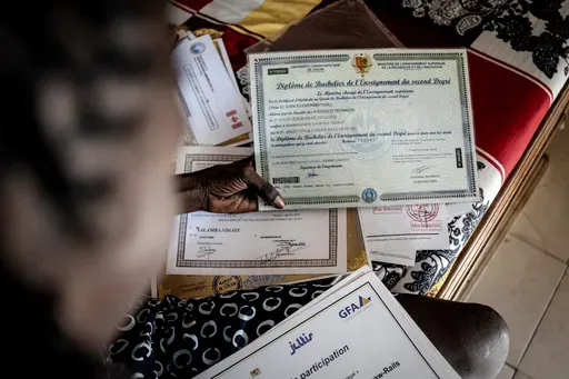 CORRECTS FAMILY NAME TO NDIAYE - Salamba Ndiaye, a 28-year-old who tried to migrate to Europe twice, checks her school certificates at her house in Thiaroye-Sur-Mer, Senegal, Friday, Aug. 23, 2024. Ndiaye is one of thousands of young Senegalese who try to flee poverty and the lack of job opportunities in the West African country each year to head to Spain. More than 22,300 people have landed on the Canary Islands from January to mid-August this year, (AP Photo/Annika Hammerschlag)
