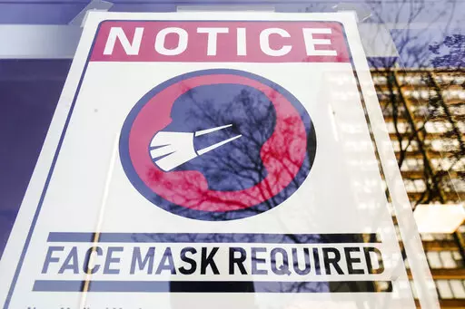 A sign requiring masks as a precaution against the spread of the coronavirus on a store front in Philadelphia, is seen Feb. 16, 2022. Philadelphia is reinstating its indoor mask mandate after reporting a sharp increase in coronavirus infections, Dr. Cheryl Bettigole, the city's top health official, announced Monday, April 11, 2022. Confirmed COVID-19 cases have risen more than 50% in 10 days, the threshold at which the city's guidelines call for people to wear masks indoors. (AP Photo/Matt Rourk