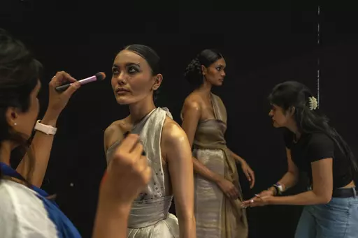 Makeup artists give final touches to models backstage before the start of a show during the Lakme Fashion Week X FDCI in Mumbai, India, Thursday, March. 9, 2023. From the front-row seats, fashion shows could be mistaken for a spectacular party with models sashaying down the ramp in stunning ensembles. But this confluence of fashion, designers, celebrities and buyers is hardly possible without an army of people furiously working behind the scenes to make sure the show goes smoothly. (AP Photo/Raf