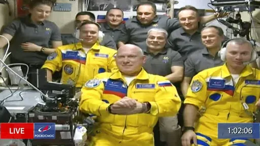 In this frame grab from video provided by Roscosmos, Russian cosmonauts Sergey Korsakov, Oleg Artemyev and Denis Matveyev are seen during a welcome ceremony after arriving at the International Space Station, Friday, March 18, 2022, the first new faces in space since the start of Russia’s war in Ukraine. The crew emerged from the Soyuz capsule wearing yellow flight suits with blue stripes, the colors of the Ukrainian flag. (Roscosmos via AP)