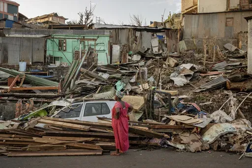 A woman looks at a destroyed home in Mamoudzou, Mayotte, Thursday, Dec. 19, 2024. (AP Photo/Adrienne Surprenant)