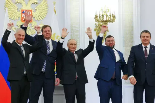 From left, Moscow-appointed head of Kherson Region Vladimir Saldo, Moscow-appointed head of Zaporizhzhia region Yevgeny Balitsky, Russian President Vladimir Putin, center, Denis Pushilin, the leader of the Donetsk People's Republic and Leonid Pasechnik, leader of self-proclaimed Luhansk People's Republic wave during a ceremony to sign the treaties for four regions of Ukraine to join Russia, at the Kremlin, Moscow, Friday, Sept. 30, 2022. The signing of the treaties making the four regions part o