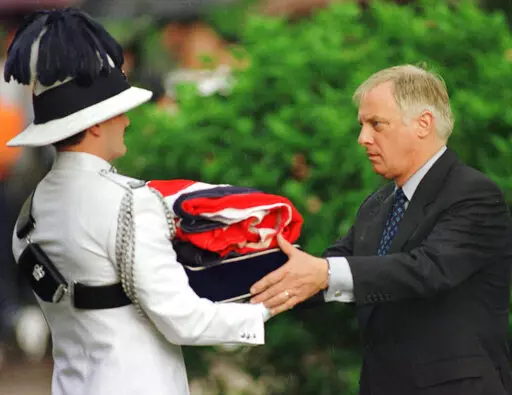 Then Gov. Chris Patten, right, receives a folded British flag after its lowering at Government House in Hong Kong on June 30, 1997 as the British colony reverts to Chinese rule at midnight. (AP Photo/Eric Draper, File)