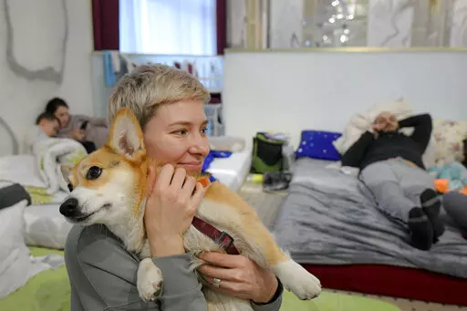 Olga Okhrimenko, 34 years-old, who fled the Russian invasion from Kharkiv on March 1, holds her dog Knolly as they sit inside a ballroom converted into a makeshift refugee shelter, in Suceava, Romania, Friday, March 4, 2022. At 4-star hotel & spa some 50 km from the border with Ukraine, wedding parties and conferences have been canceled and the ballroom converted into a makeshift refugee shelter where those who have escaped the Russian invasion come to rest and warm up before continuing their jo