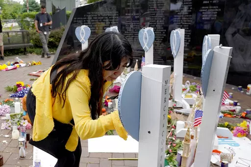 Yesenia Hernandez, granddaughter to Nicolas Toledo, who was killed during Monday's Highland Park., Ill., Fourth of July parade, writes on a memorial for Toledo along with the six others who lost their lives in the mass shooting, Wednesday, July 6, 2022, in Highland Park. (AP Photo/Charles Rex Arbogast)