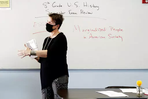 History teacher Wendy Leighton holds a copy of "They Called us Enemy," about the internment of Japanese Americans, while speaking about marginalized with her students at Monte del Sol Charter School, Dec. 3, 2021, in Santa Fe, N.M. Americans are deeply divided over how much children in K-12 schools should be taught about racism and sexuality. That's according to a new poll from the University of Chicago Harris School of Public Policy and The Associated Press-NORC Center for Public Affairs Resear