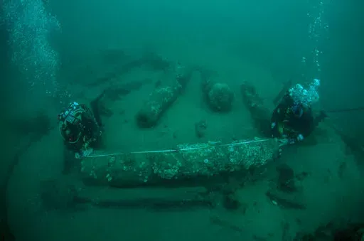 In this undated photo provided by Norfolk Historic Shipwrecks, Julian And Lincoln Barnwell measure the cannon found on the HMS Gloucester in 2007. Excavators and historians are telling the world about the wreck of a royal warship that sank in 1682 while carrying the future king James Stuart. The HMS Gloucester ran aground while navigating sandbanks off the town of Great Yarmouth on the eastern English coast. The wreck of the Gloucester was found in 2007 by brothers Julian and Lincoln Barnwell an