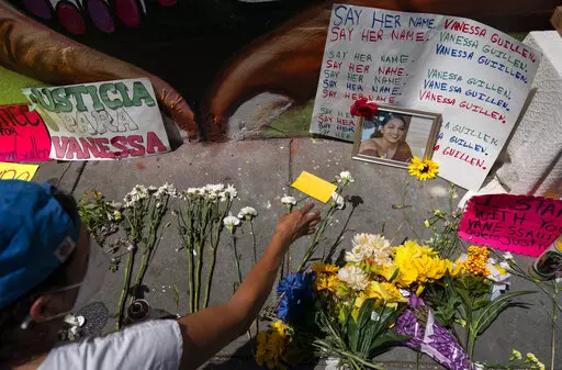 Frida Larios places flowers near of photograph of slain Army Spc. Vanessa Guillen at the base of a mural of Guillen on 14th Street NW in Washington, July 13, 2020. Guillen was killed by a soldier, who her family says sexually harassed her, and who killed himself as police sought to arrest him. (AP Photo/Carolyn Kaster, File)