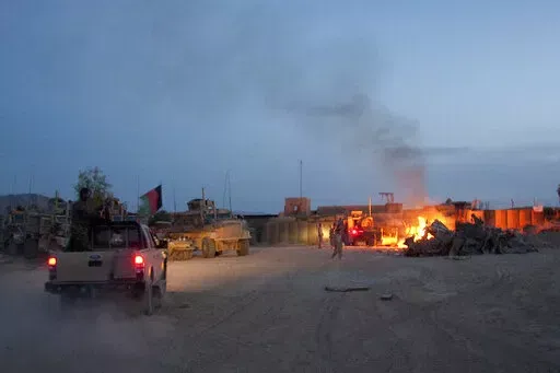 An Afghan National Army pickup truck passes parked U.S. armored military vehicles, as smoke rises from a fire in a trash burn pit at Forward Operating Base Caferetta Nawzad, Helmand province south of Kabul, Afghanistan, April 28, 2011. The Senate is expected to approve on Thursday a large expansion of health care and disability benefits for veterans of Iraq and Afghanistan in response to concerns about their exposure to toxic burn pits.  (AP Photo/Simon Klingert, File)