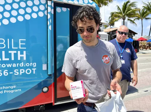 Huston Ochoa, a clinical counselor for The Spot, hands out samples of Narcan, which can reduce opioid overdoses, to spring breakers on Fort Lauderdale Beach, Fla., on March 31, 2022.  Community activists are warning spring breakers of a surge in recreational drugs being laced with the dangerous opioid fentanyl, and offered them an antidote for overdoses _ which have risen nationally during the COVID-19 pandemic. (AP Photo/Freida Frisaro)