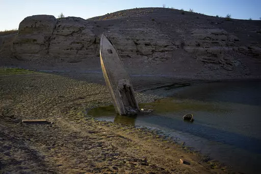 A formerly sunken boat sits upright into the air with its stern stuck in the mud along the shoreline of Lake Mead at the Lake Mead National Recreation Area, Friday, June 10, 2022, near Boulder City, Nev. The identification of bones found in May on the receding shoreline of Lake Mead has resurfaced family memories of a 42-year-old Las Vegas father believed to have drowned 20 years ago. (AP Photo/John Locher, File)
