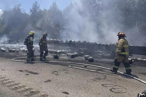 In this photo released by the Mississippi Highway Patrol, firefighters work to stop a fire from spreading from a semitrailer, which was carrying propane tanks, on Interstate 59 near Poplarville, Miss., on Monday, Aug. 14, 2023. The interstate was closed after the truck caught fire. (Mississippi Highway Patrol via the Mississippi Department of Public Safety via AP)