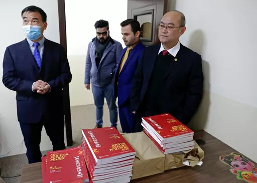 Chinese lecturer, Zhiwei Hu, left, teachers and officials of the Chinese Language Department stand in front of Chinese language books intended for students in Salahaddin University in Irbil, Iraq, Wednesday, Jan. 19, 2021. The Chinese language school in northern Iraq is attracting students who hope to land jobs with a growing number of Chinese companies in the oil, infrastructure, construction, and telecommunications sectors in the region. (AP Photo/Khalid Mohammed)