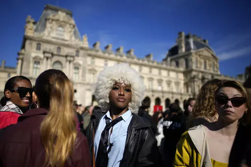 Fashion lovers wait in the courtyard of the Louvre museum during Louis Vuitton ready-to-wear Spring/Summer 2023 fashion collection presented Tuesday, Oct. 4, 2022 in Paris. (AP Photo/Christophe Ena)