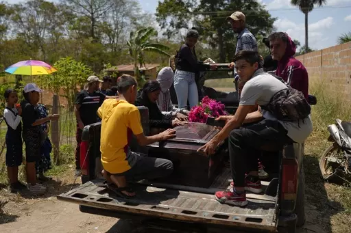 The coffin that contains the remains of miner Gerson Leal, is transported in the bed of a truck to a cemetery in La Paragua, Bolivar state, Venezuela, Thursday, Feb. 22, 2024. The collapse of an illegally operated open-pit gold mine in central Venezuela killed at least 14 people including Leal and injured several more, state authorities said Wednesday, as some other officials reported an undetermined number of people could be trapped. (AP Photo/Ariana Cubillos)