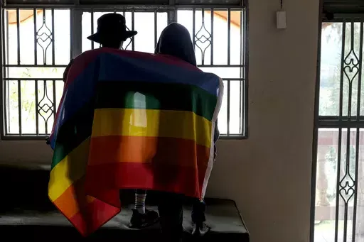 A gay Ugandan couple cover themselves with a pride flag as they pose for a photograph in Uganda on March 25, 2023. Uganda's president Yoweri Museveni has signed into law tough new anti-gay legislation supported by many in the country but widely condemned by rights activists and others abroad, it was announced Monday, May 29, 2023. (AP Photo, File)