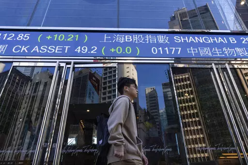 A pedestrian passes by the Hong Kong Stock Exchange electronic screen in Hong Kong, on Wednesday, March 1, 2023. Asian shares were mixed Wednesday as investors watched for upcoming earnings reports and other indicators on how inflationary pressures might be denting global growth. (AP Photo/Louise Delmotte)