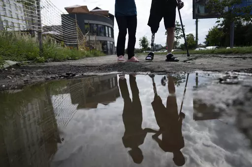 Roman Yarmolenko, a Ukrainian soldier from the 93rd brigade, learns to walk on a prosthetic leg. He crosses rough, muddy terrain outside the Unbroken rehabilitation center in Lviv, Ukraine, Wednesday, July 26, 2023. Ukraine is facing the prospect of a future with upwards of 20,000 amputees, many of them soldiers who are also suffering psychological trauma from their time at the front. (AP Photo/Evgeniy Maloletka)