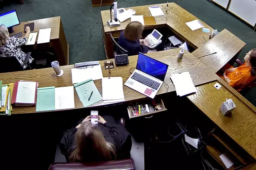 In this image from security camera video, Lincoln County District Judge Traci Soderstrom looks at her cellphone during a murder trial, June 12, 2023, at the Lincoln County District Court in Chandler, Okla. Chief Justice of the Oklahoma Supreme Court John Kane IV is recommending the removal of the district court judge who exchanged more than 500 texts with her bailiff during a murder trial. An investigation by the Oklahoma Supreme Court Council on Judicial Complaints found Soderstrom mocked prose