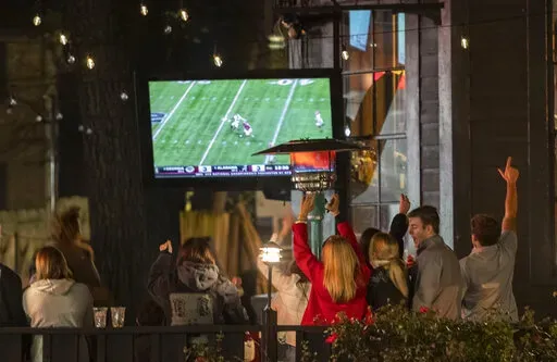 Alabama fans react as they watch television coverage of the College Football Playoff national championship game against Georgia, Monday, Jan. 10, 2022, in Tuscaloosa, Ala.  Brookfield Business Partners is boosting its buyout offer for Nielsen Holdings, Tuesday, March 29, 2022, to about $16 billion after the TV ratings and marketing data company rejected a $9 billion takeover bid.  (AP Photo/Vasha Hunt, File)