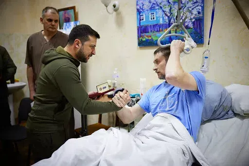 In this photo provided by the Ukrainian Presidential Press Office on Sunday, March 13, 2022, President Volodymyr Zelenskyy, center, shakes hands with a wounded soldier during his visit to a hospital in Kyiv, Ukraine. (Ukrainian Presidential Press Office via AP)