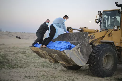 Bulldozer carries the bodies of Palestinians killed in the north of the Gaza Strip and turned over by the Israeli military during a mass funeral in Rafah, Tuesday, Dec. 26, 2023. (AP Photo/Hatem Ali)