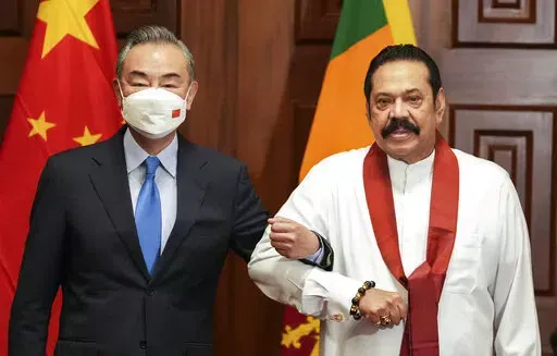 Chinese Foreign Minister Wang Yi, left, poses for media before his meeting with Sri Lankan Prime Minister Mahinda Rajapaksa in Colombo, Sri Lanka, Sunday, Jan. 9, 2022. (AP Photo/Eranga Jayawardena)
