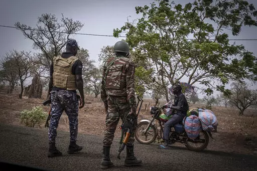 A police officer and a soldier from Benin stop a motorcyclist at a checkpoint outside Porga, Benin, March 26, 2022. Porga, in the Atakora region of northern Benin bordering Burkina Faso, has suffered several jihadist attacks. Violence linked to al-Qaida and the Islamic State group, which has wracked much of West Africa's Sahel region for more than seven years is spreading into the coastal states and Benin has become the hardest hit. According to the Armed Conflict Location & Event Data Project, 