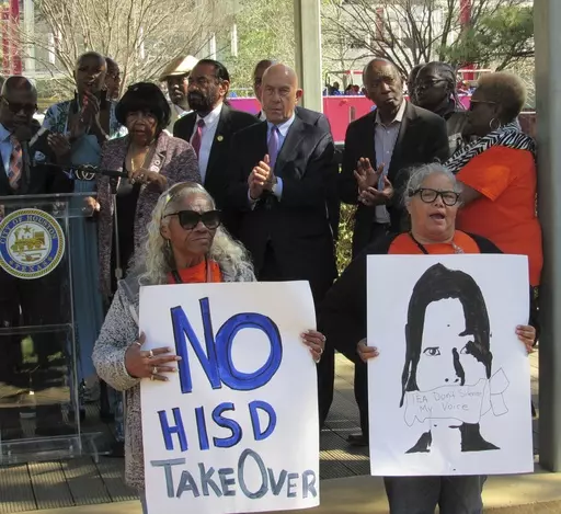 People hold up signs at a news conference, Friday, March 3, 2023, in Houston while protesting the proposed takeover of the city's school district by the Texas Education Agency. Texas officials on Wednesday, March 15, announced a state takeover of Houston's nearly 200,000-student public school district, the eighth-largest in the country, acting on years of threats and angering Democrats who assailed the move as political. (AP Photo/Juan A. Lozano)