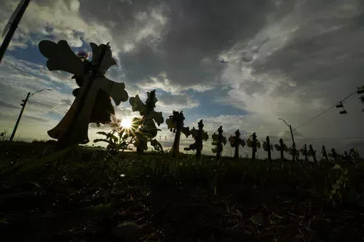 Vehicles pass crosses placed to honor the victims of the shootings at Robb Elementary School, Thursday, Aug. 25, 2022, in Uvalde, Texas. The Texas Department of Public Safety has fired an officer who was at the scene of the school massacre and becomes the first member of the state police force to lose their job in the fallout over the hesitant response to the May attack. (AP Photo/Eric Gay, File)