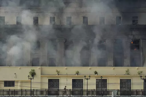 A man passes by the still smoldering Manila Central Post Office after it caught fire early Monday, May 22, 2023 in Manila, Philippines. On Friday, July 7, The Associated Press reported on stories circulating online incorrectly claiming a video shows a major library in France burning during riots sparked by the police killing of a 17-year-old. (AP Photo/Aaron Favila, File)