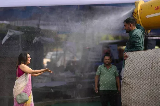 A polling official enjoys a cooling spray of water under intense heat at a distribution venue for Electronic Voting Machines (EVMs) and other election material on the eve of the fifth phase of polling in the six-week-long national election in Lucknow, India, Sunday, May 19, 2024. A top United Nations official says even though climate change makes disasters such as cyclones, floods and droughts more intense, more frequent and striking more places, fewer people are dying from those catastrophes gl