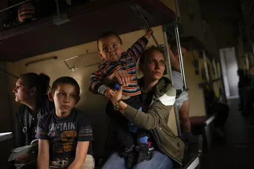 Yana Skakova and her son Yehor who fled from Lysychansk with other people sit in an evacuation train at the train station in Pokrovsk, eastern Ukraine, eastern Ukraine, Saturday, May 28, 2022. Fighting has raged around Lysychansk and neighbouring Sievierodonetsk, the last major cities under Ukrainian control in Luhansk region. (AP Photo/Francisco Seco)