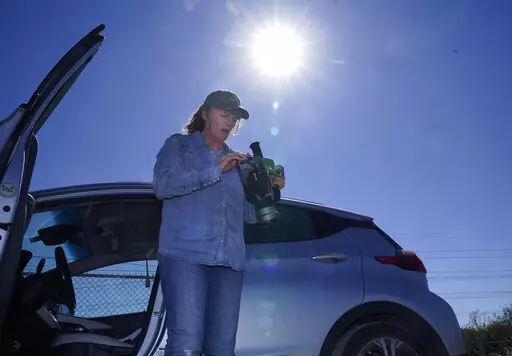 Sharon Wilson sets up a thermal imaging camera near a compressor station in Arlington, Texas, Tuesday, Oct. 18, 2022. Wilson, a field advocate for Earthworks, which promotes alternatives to fossil fuels, uses the high-tech camera to detect methane leaks at oil and gas facilities.  (AP Photo/LM Otero)