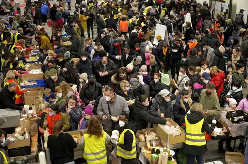 Ukrainian refugees queue for food in the welcome area after their arrival at the main train station in Berlin, Germany, March 8, 2022. The Ukraine war has turned the basement of Berlin’s glass-and-steel main train station into a sprawling refugee town where a small army of volunteers in yellow and orange vests offer everything from shampoo to cell phone chargers to exhausted refugees. (AP Photo/Michael Sohn, File)