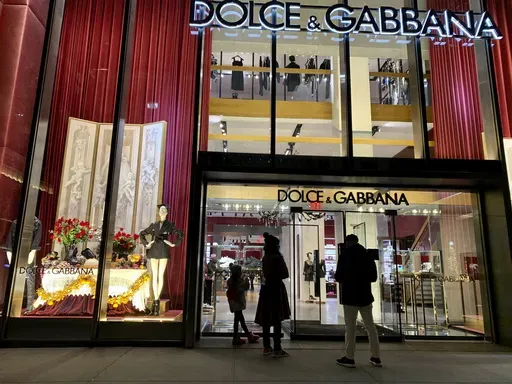 People stand outside the Dolce & Gabbana store on Fifth Avenue, Nov. 21, 2021, in New York. (AP Photo/Pamela Hassell, File)