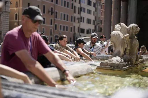 People cool off at a fountain in front of the Pantheon, in Rome, Saturday, Aug. 19, 2023, where temperatures were expected to reach as high as 37 Celsius (98 Farenheit). This was the hottest summer on record across the globe, forcing many tourists to rethink how and where they travel. (AP Photo/Andrew Medichini, FIle)