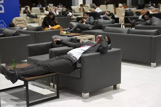 Attendees and members of the media lounge as they wait for a closing plenary session at the COP27 U.N. Climate Summit, Sunday, Nov. 20, 2022, in Sharm el-Sheikh, Egypt. (AP Photo/Peter Dejong)