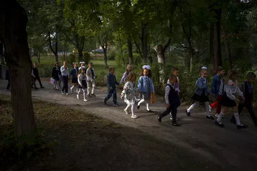 Students walk together entering in their class during their first day of school at a public school in Irpin, Ukraine, Thursday, Sept. 1, 2022. Ukrainian children return to school without sharing memories from their holidays. They share stories of how they survived the first months of the war. For many children, last semester finished the day before Russia invaded Ukraine on the 24th of February. The ongoing war remains the biggest challenge for the educational system of Ukraine. (AP Photo/Emilio