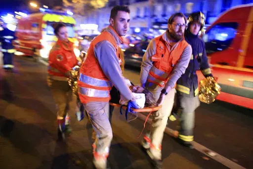 A woman is evacuated from the Bataclan concert hall after a shooting on Nov. 13, 2015 in Paris. The historic trial in Paris of 20 men suspected of critical roles in the Islamic State massacres that killed 130 people in 2015 has ended this week with verdicts against the defendants in France's worst peacetime attack expected on Wednesday June 29. (AP Photo/Thibault Camus, File)