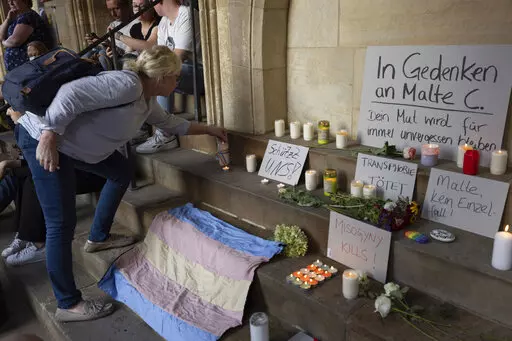 A woman lights a candle in memory of Malte C., the 25-year-old man who has died from injuries suffered in an attack at a gay pride event in the western city of Muenster, during a demonstration to condemn violence against LGBT people, in Muenster, Germany, Friday Sept. 2, 2022. (Friso Gentsch/dpa via AP)
