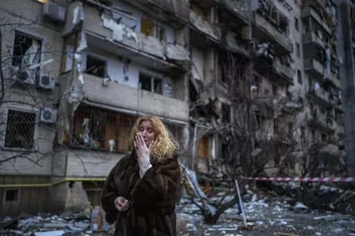 Natali Sevriukova reacts next to her house following a rocket attack the city of Kyiv, Ukraine, on Feb. 25, 2022. The yearlong war in Ukraine has left tens of thousands of dead and wounded on both sides, disrupted energy and food supplies, and reduced whole cities to ruins. (AP Photo/Emilio Morenatti, File)