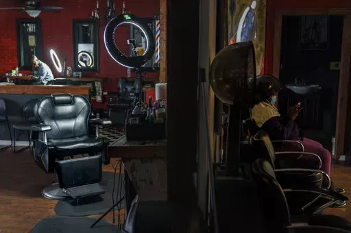 The barber chair where Sherman Peebles used to cut hair on Saturdays sits empty at Overflo Beauty and Barber Shop in Columbus, Ga., Wednesday, March 9, 2022. In late September, as Peebles, who also worked as a sheriff's deputy, lay in a hospital bed, COVID-19's toll reached 675,000, surpassing the number of Americans killed by the Spanish flu pandemic a century ago. He died at age 49 the next day. Months later, his best friend and shop owner, Gerald Riley, still arrives at the shop each Saturday