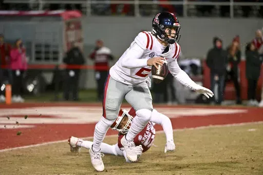 Mississippi quarterback Jaxson Dart (2) tries to get away from Arkansas defensive lineman Jashaud Stewart (58) during the first half of an NCAA college football game Saturday, Nov. 19, 2022, in Fayetteville, Ark. (AP Photo/Michael Woods)