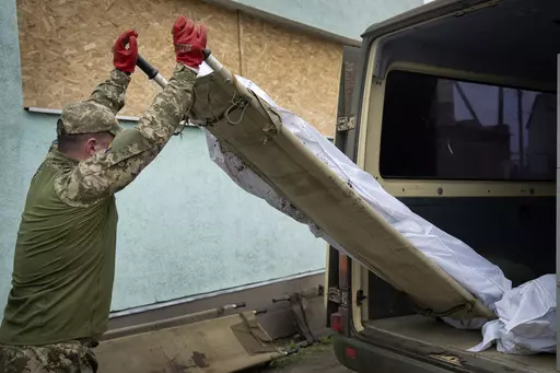 A Ukrainian soldier loads the bodies of killed Ukrainian servicemen into a van near Bakhmut, Donetsk region, Ukraine, Thursday, May 25, 2023. (AP Photo/Efrem Lukatsky)